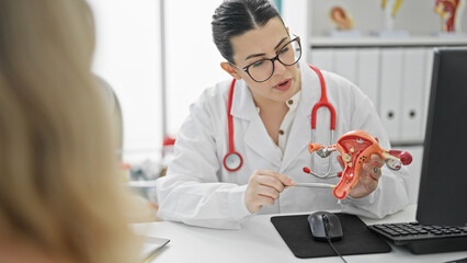 Young beautiful hispanic woman doctor showing female reproductive system at the clinic