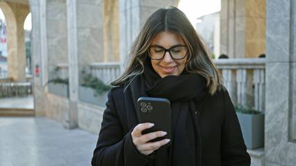 A smiling young woman checks her smartphone on an istanbul street, bringing european urban charm to...