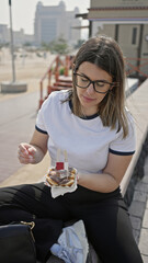 A young woman enjoys poffertjes drizzled with chocolate in an urban qatar setting.