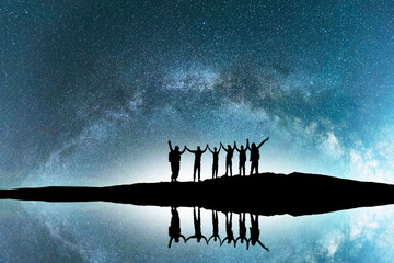 Silhouette of a hikers standing on the lake beach with reflection, on the milky way galaxy background. - obrazy, fototapety, plakaty