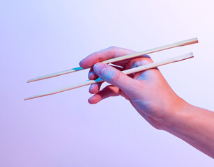 Hands holding Chinese sticks, food chopsticks, neon light