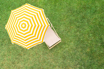 Yellow umbrella with deck chair on the green grass sunbathes at summer day. Top view, drone, aerial view. - 721527876
