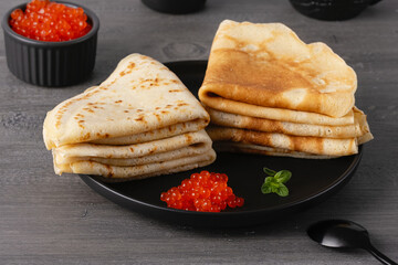 Pancakes with red caviar. Close-up of pancakes stacked on grey background