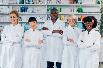 Professionals are standing in the pharmacy with their arms crossed.