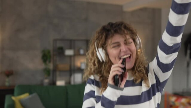 One woman with headphones at home listen music online happy smile sing