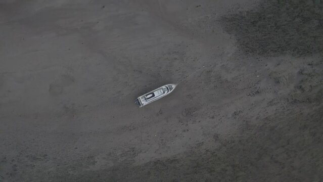 Aerial Drone View of a Boat Resting on the Calm Sand at Low Tide, in the Harbor on the Calm Beach Taken Using the Roll Technique.