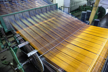Modern Carpet weaving factory. Carpet making machine needle. Yarn bobbins attached to a carpet...