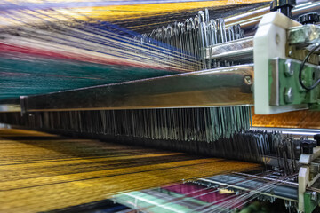 Modern Carpet weaving factory. Carpet making machine needle. Yarn bobbins attached to a carpet...