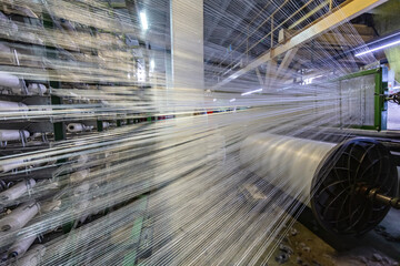 Modern Carpet weaving factory. Carpet making machine needle. Yarn bobbins attached to a carpet...