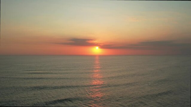 4K Aerial drone stable footage of sunset on the beach, orange golden sky on a calm summer beach.