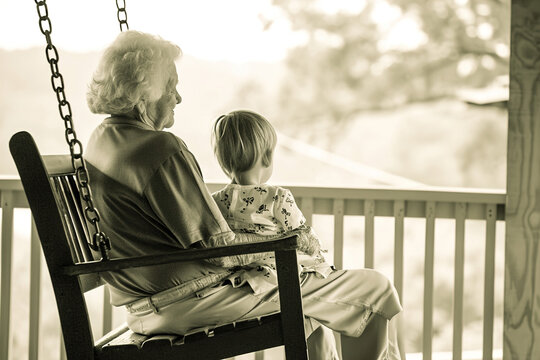 Quiet moments of reflection and bonding, such as grandparents and grandchildren sitting together on a porch swing.