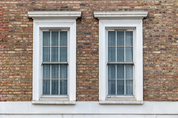 two classic white windows of typical london architecture with red brick wall