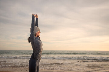sporty woman doing stretching execises at the beach, winter fitness.