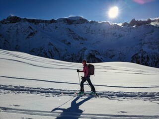 Woman on a ski tour towards the summit in a breathtaking mountain landscape. Fanenstock Elm ski tour. In the background Piz Sardona Segnas ​. High quality photo