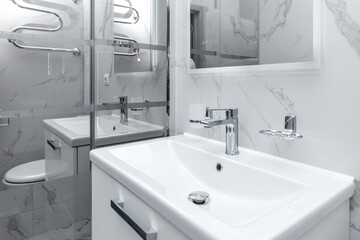 There is a sink and a shower stall in the shower room. Stylish black and white interior design