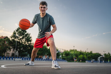Fototapeta premium One caucasian teenager stand on basketball court with ball