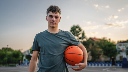 One caucasian teenager stand on basketball court with ball