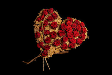 red roses in wicker heart floral arrangement on black background