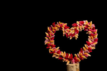dried flowers tied as heart shape on black background with space for text

