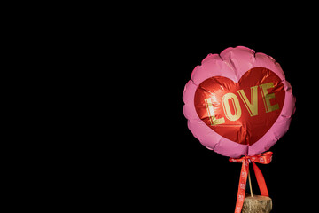 pink balloon with heart shape and test "Love" with black background and space for text.