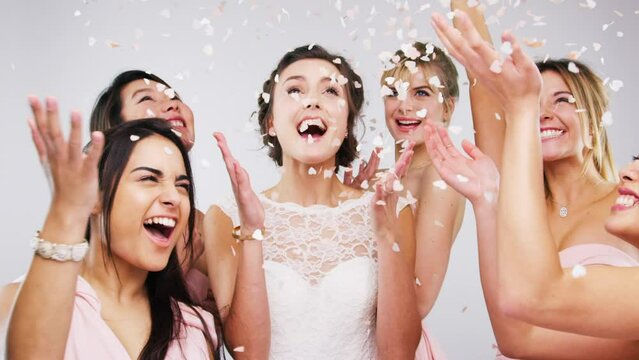 Bridesmaids, happy and confetti with bridal party, dancing and excited for friends wedding, energy or group. Young women, celebration and entertainment for marriage, photobooth and studio background