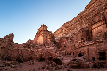 Fototapeta premium Tombs line along a hill on the Street of Facades in the ancient Jordanian city of Petra called the Valley of the Kings. Hot sunny day