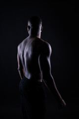 Fototapeta na wymiar One young african muscular build man standing topless silhouette isolated on black background