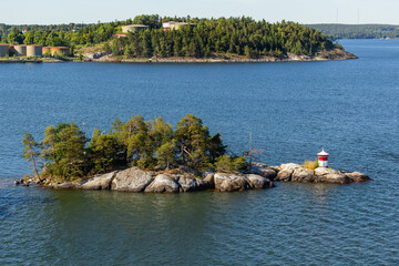 Small red and white lighthouse on island near Stockholm, capital of Sweden. Overhead view of technical building for navigating ships on sunny day. Summer boat trip in Scandinavia.