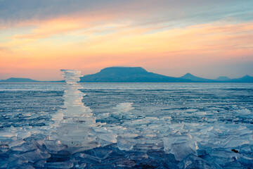 Fonyod, Hungary - Beautiful icebergs on the shore of the frozen Balaton. Badacsony and Gulacs with...