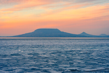 Fonyod, Hungary - Beautiful icebergs on the shore of the frozen Balaton. Badacsony and Gulacs with...