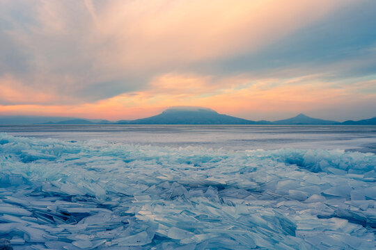 Fonyod, Hungary - Beautiful icebergs on the shore of the frozen Balaton. Badacsony and Gulacs with a spectacular cloudy sunset in the background. Winter landscape.
