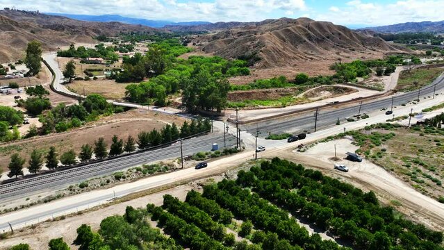 San Timoteo Canyon at the Train Rail Crossing with cars using the road near an Orange Grove in Redlands California