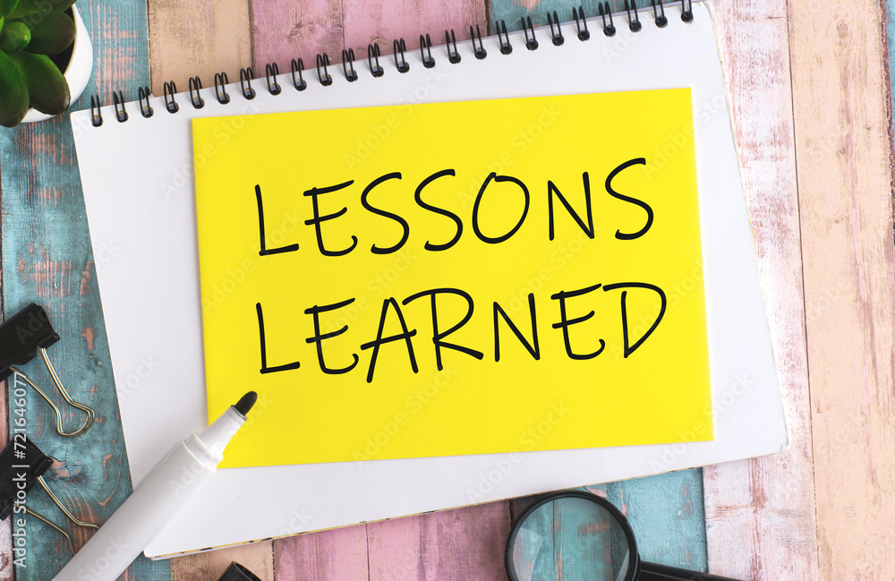 Poster text lessons learned on yellow paper composition with stationery on color background