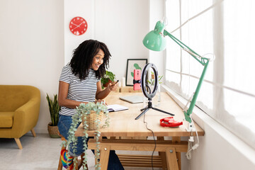 Young content creator woman live streaming at home using mobile phone. Millennial influencer female...