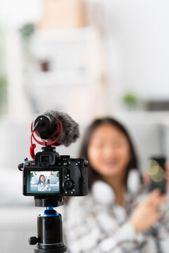 Vertical photo of a chinese blogger recording an online video at home