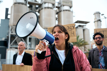 Angry and rebellious woman speaking and protesting with megaphone at demonstration at climate...