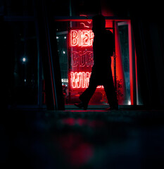 silhouette of a person passing a neon sign wall