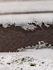 Portrait of a ditch with water that is impressively frozen with crystals in winter