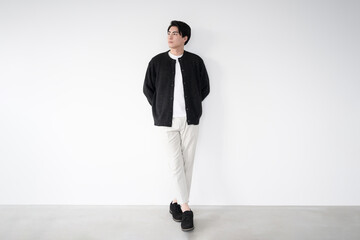 白い壁の前に立つ男性　ファッションのイメージ