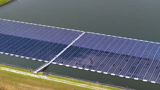 Generation of renewable electricity on water surface with no air pollution. Industrial pond with floating photovoltaic solar panels for producing clean electrical energy