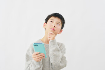 スマートフォンを持って考える男の子　白背景