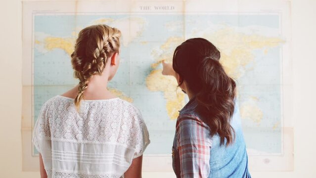 Back, people and world map on wall for travel, vacation and holiday destination choice. Rear view, women and geography for journey, friends talking together and tourist plan location for adventure