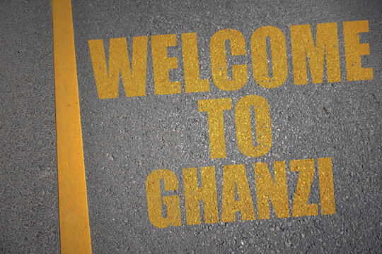 asphalt road with text welcome to Ghazni near yellow line.