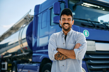 Confident truck driver in front of his vehicle looking at camera.