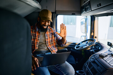 Happy black truck driver making video call from vehicle cabin. - obrazy, fototapety, plakaty