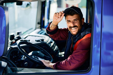 Happy driver behind steering wheel of truck looking at camera. - obrazy, fototapety, plakaty