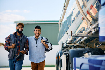 Happy black truck driver and his colleague walking on parking lot.