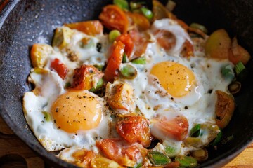 Red shakshuka. Fried eggs with tomatoes and onions, leek in a frying pan, close up