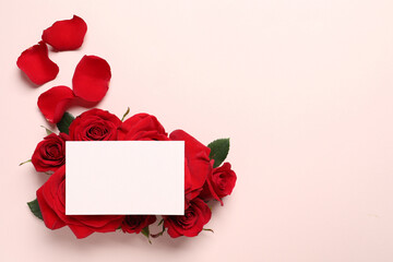 Blank card, beautiful red roses and petals on pale pink background, top view. Space for text