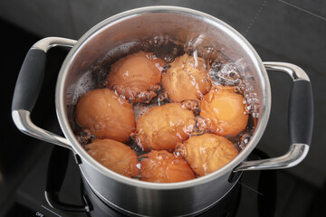 Chicken eggs boiling in pot on electric stove, above view